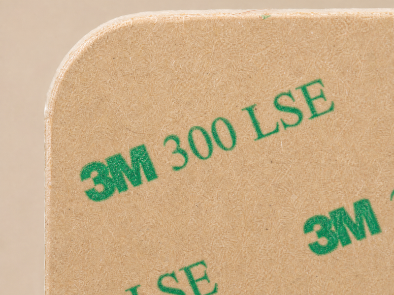 Nahaufnahme einer beigen Fläche mit grüner Aufschrift 3M 300 LSE, die die Ecke einer Klebefolie zeigt.