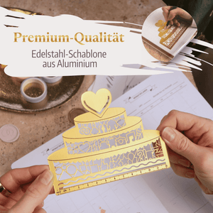 Jemand hält die goldene Lineal-Clip-Schablone "Hochzeitstorte" von Mein kleines Hochzeitsbüro in Herz- und Tortenform mit Cut-Out-Muster und Linealrand. Text: Premium-Qualität Edelstahl-Schablone aus Aluminium.