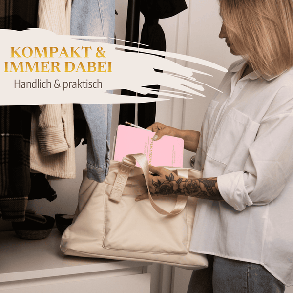 Eine Frau in weißem Hemd und Jeans packt "Mein kleines Hochzeitsbuch - Zuckerwatten Herzchen" von Mein kleines Hochzeitsbüro in eine beigefarbene Tragetasche neben ihrem offenen Kleiderschrank. Text: Kompakt  immer dabei. Handlich  praktisch.