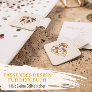 Zwei extragroße Stiftehalter - Schlaufe von Mein kleines Hochzeitsbüro mit goldenen Herzen stehen auf dem Schreibtisch neben einem Notizbuch - stilvolles Accessoire und perfekte Unterstützung für deinen Hochzeitsplaner.