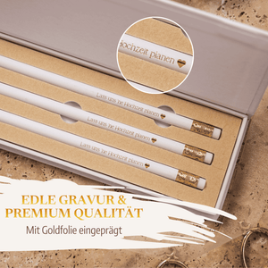 Das Bleistift-Set - Lass uns 'ne Hochzeit planen von Mein kleines Hochzeitsbüro besteht aus drei weißen Bleistiften mit Goldgravur, die sich perfekt für die Hochzeitsplanung eignen und in einer Nahaufnahme die stilvollen Goldfoliendetails hervorheben.