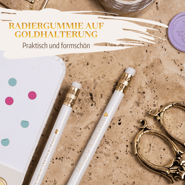 Zwei weiße Bleistifte mit goldenem und weißem Radiergummi aus dem Bleistift-Set von Mein kleines Hochzeitsbüro - Lass uns 'ne Hochzeit planen liegen auf einer Murmel neben einem gepunkteten Notizbuch, einer goldenen Schere und einem lila Wachssiegel - ideal für die Hochzeitsplanung. Text: Radiergummie auf Goldhalterung.